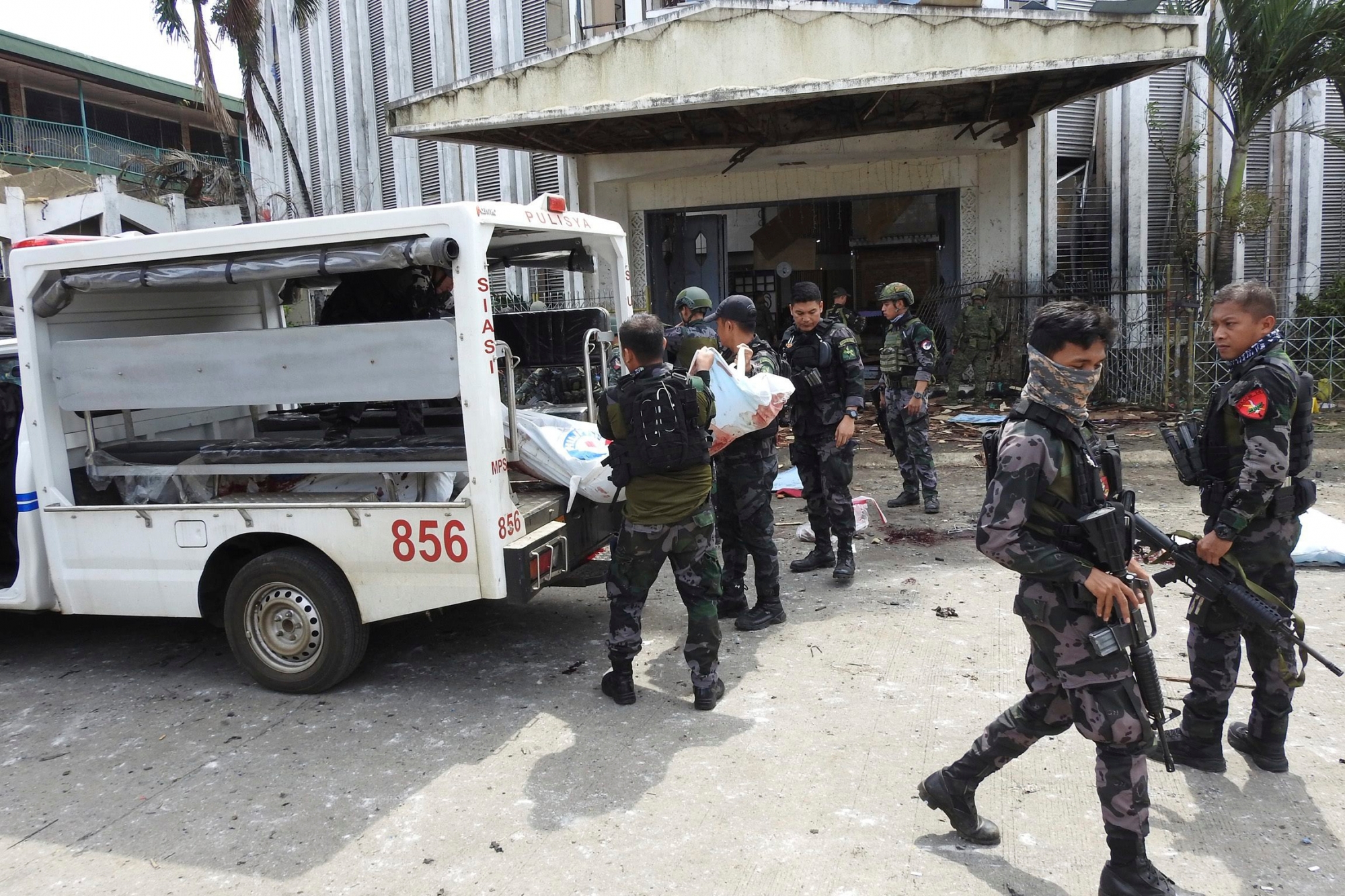 Police remove a body of a victim from the scene after two bombs exploded outside a Roman Catholic cathedral in Jolo, the capital of Sulu province in southern Philippines, Sunday, Jan. 27, 2019. Two bombs minutes apart tore through a Roman Catholic cathedral on a southern Philippine island where Muslim militants are active, killing at least 20 people and wounding more than 80 others during a Sunday Mass, officials said. (AP Photo/Nickee Butlangan) Philippines Church Attack