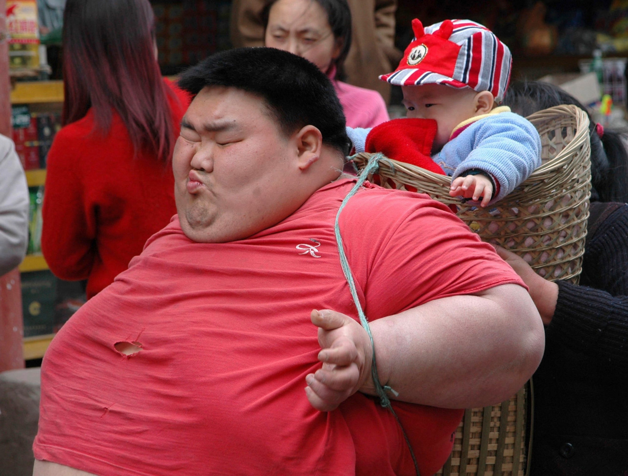 Twenty-six year-old Liang Yong carries his child in a basket in China's Chongqing Municipality, Monday April 17, 2006.  Liang, who weighed 220 kg at his heaviest, had slimmed down to 110 kg after receiving treatment for obesity at age 23.  But his weight increased to 210kg after marrying his wife Tang Xiaoyan, who gave birth to a child. China's Health Ministry says that 200 million Chinese are overweight, while the number of people considered clinically obese has nearly doubled to 60 million, or 7.1 percent of adults, since 1992.  (KEYSTONE/AP Photo/EyePress) ** CHINA OUT ** CHINA OBESITY