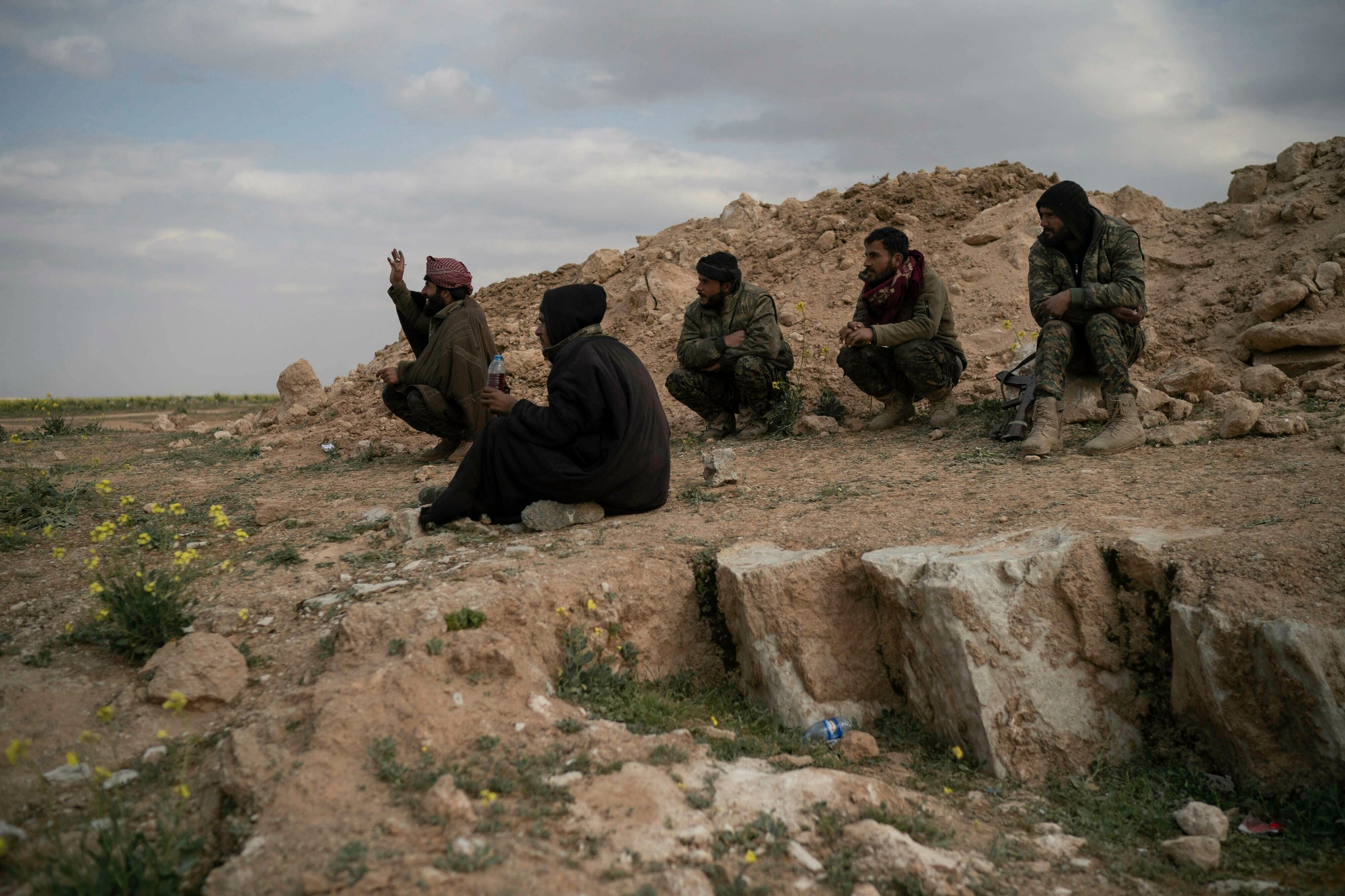 U.S.-backed Syrian Democratic Forces (SDF) fighters sit atop a hill in the desert outside the village of Baghouz, Syria, Thursday, Feb. 14, 2019. U.S.-backed Syrian forces are clearing two villages in eastern Syria of remaining Islamic State militants who are hiding among the local population, and detaining others attempting to flee with the civilians, the U.S.-led coalition said Thursday. (AP Photo/Felipe Dana) Syria