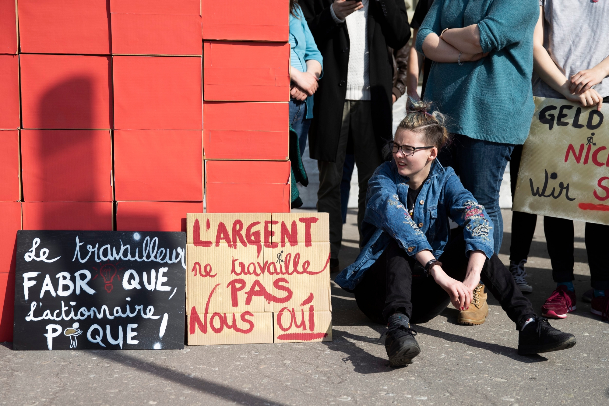 Ein Mitglied der JUSO sitzt neben den Schachteln mit den Unterschriften, bei der Einreichung der 99-Prozent-Initiative, am Dienstag, 2. April 2019 in Bern. (KEYSTONE/Peter Klaunzer) SCHWEIZ EINREICHUNG 99-PROZENT-INITIATIVE