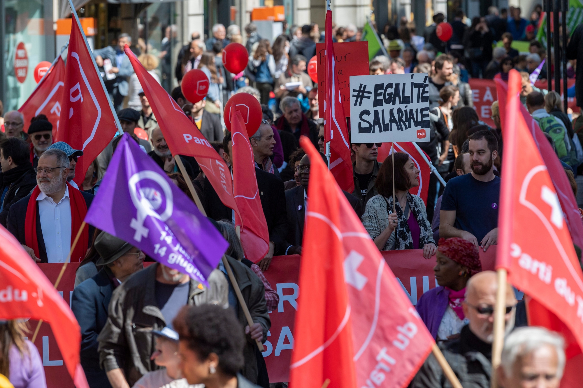 Des manifestants avec des pancartes et des drapeaux defilent dans les rues de Geneve, lors du defile du 1er mai - Fete du Travail , ce mercredi 1 mai 2019 a Geneve. A Geneve, pres de 2'000 personnes ont participe au traditionnel cortege du 1er mai place, cette annee, sous le signe de lÕegalite, greve des femmes et la justice sociale et le climat. (KEYSTONE/Martial Trezzini) SUISSE DEMO 1 MAI TRAVAIL