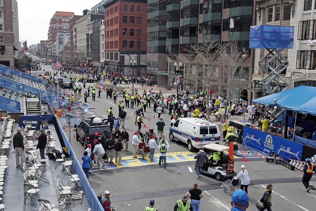 People react to an explosion at the 2013 Boston Marathon in Boston, Monday, April 15, 2013. Two explosions shattered the euphoria of the Boston Marathon finish line on Monday, sending authorities out on the course to carry off the injured while the stragglers were rerouted away from the smoking site of the blasts. (AP Photo/The Boston Herald,  Stuart Cahill) BOSTON GLOBE OUT; METRO BOSTON OUT; MAGS OUT;