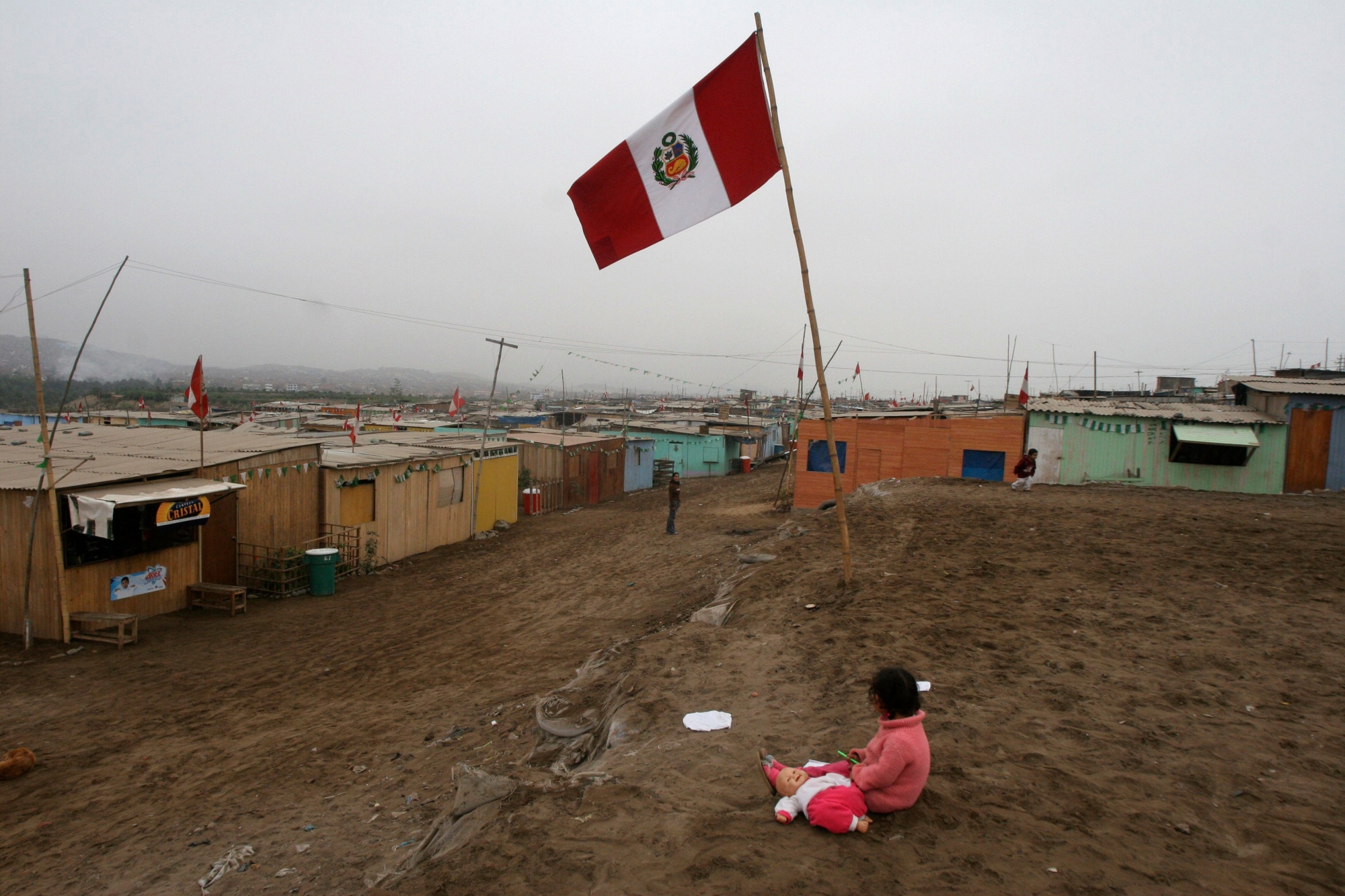 A girl sits with her doll next to a flag of Peru in a poor neighborhood in Lima, Thursday, May 15, 2008. Leaders from nearly 60 Latin America and European countries will attend a Friday summit in Peru to discuss climate change, trade, poverty and the global food crisis. (KEYSTONE/AP Photo/Esteban Felix) PERU LATAM EU SUMMIT