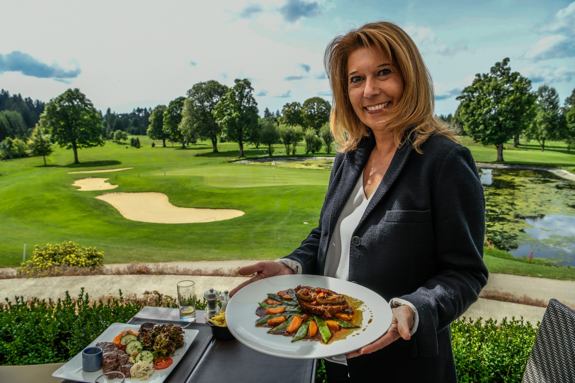 Diana Barbacci Lévy pose avec son plat devant le cadre idyllique du golf des Bois.