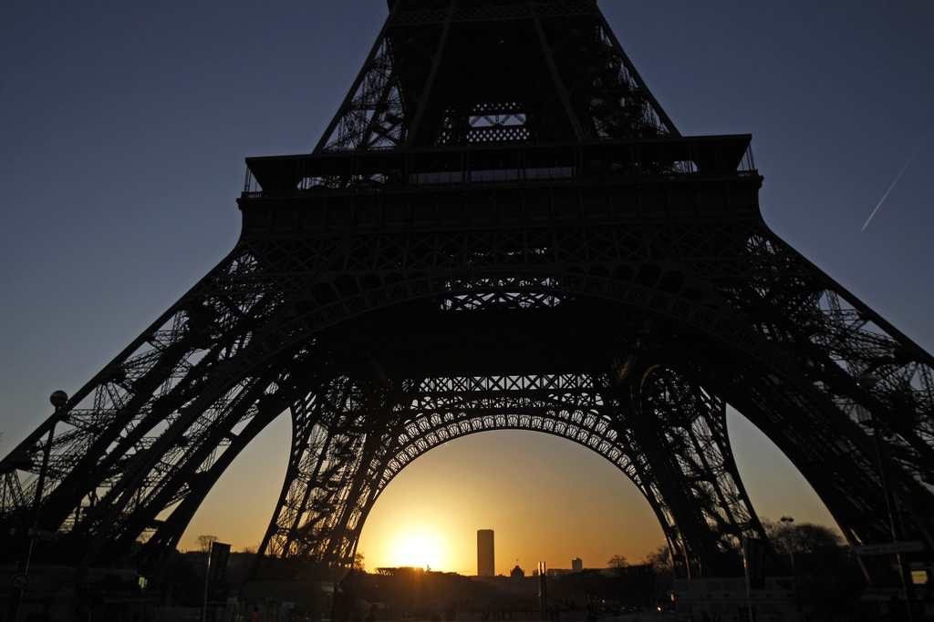 The sun rises behind the Eiffel Tower in Paris, Saturday, Jan. 14, 2012. (AP Photo/Michel Euler)