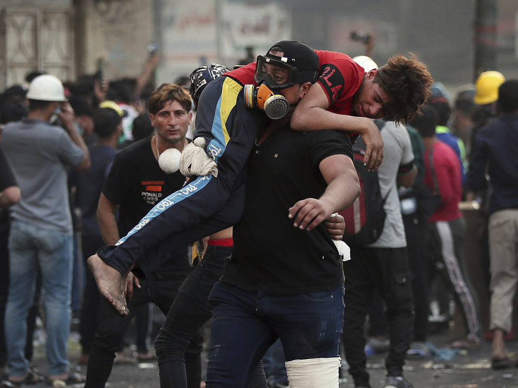 Un manifestant emmène un de ses camarades, blessé dans les affrontements avec les forces de l'ordre irakienne, à Baghdad
