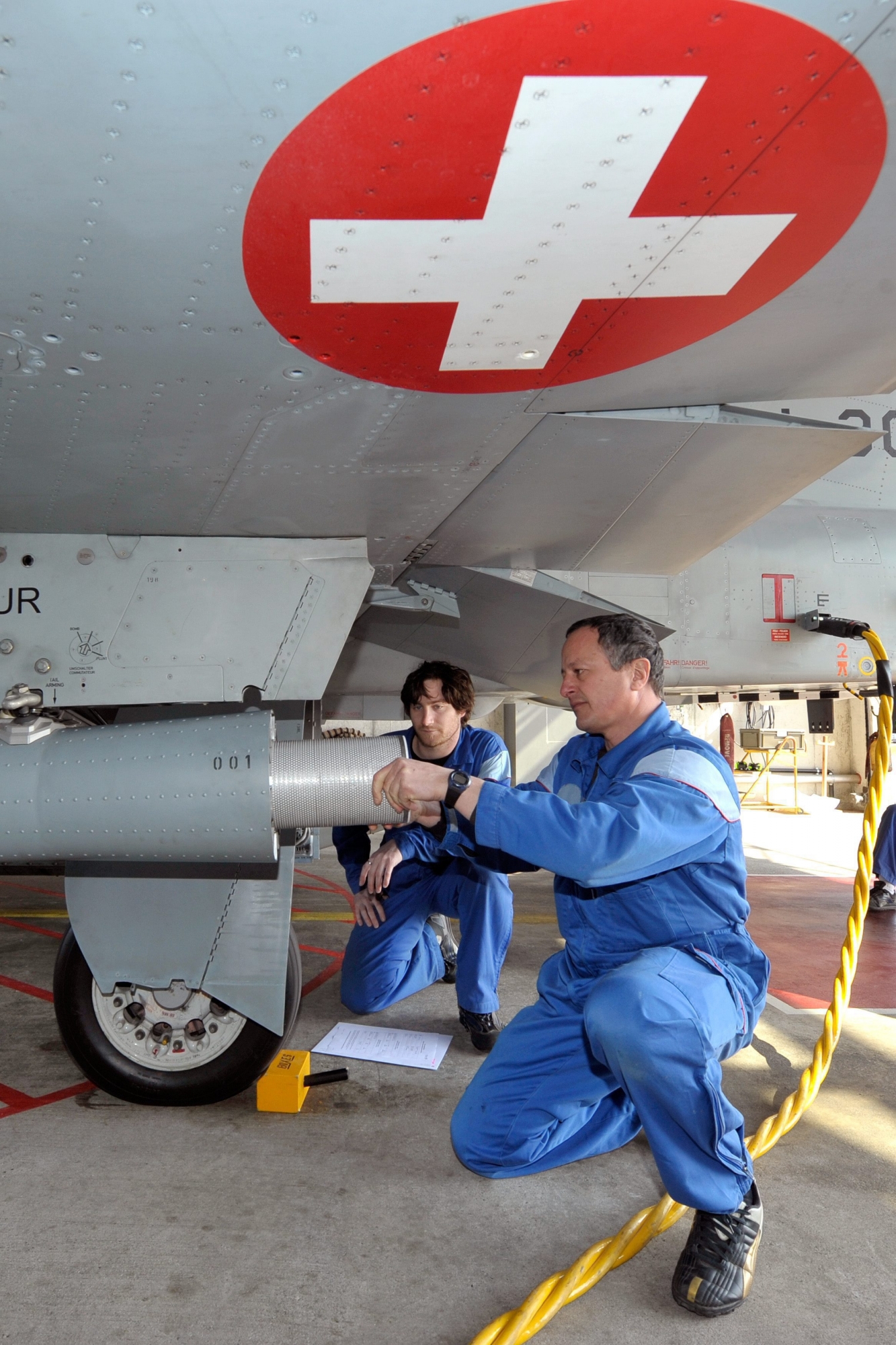 A worker removes a aerosol collector of a Swiss Air Force F-5E Tiger aircraft in Payerne after a radioactivity measurements flight over Switzerland, Wednesday March 23, 2011. An aerosol collector is located under each wings of the aircraft and filters the air to collect fines particles at an altitude of 6,000 meters (19,684 feet). The Federal Office of Public Health (FOPH) has been conducting flights on a regular basis in the past years to monitor the radioactivity but due to the situation in Japan decided to increase them until end of March 2011. (KEYSTONE/Dominic Favre) SWITZERLAND