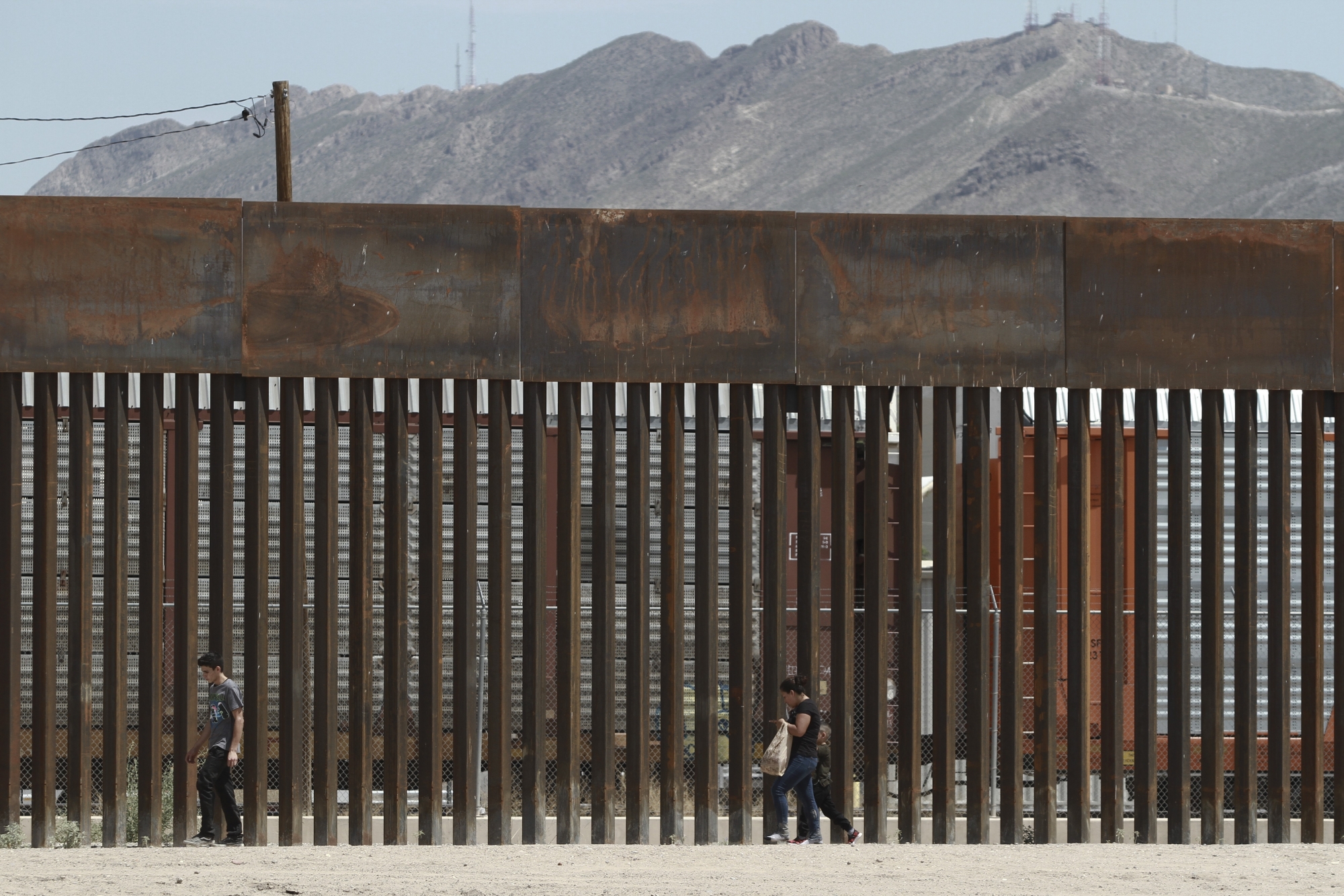 FILE - In this July 17, 2019 file photo, three migrants who had managed to evade the Mexican National Guard and cross the Rio Grande onto U.S. territory walk along a border wall set back from the geographical border, in El Paso, Texas, as seen from Ciudad Juarez, Mexico.  (AP Photo/Christian Chavez) Immigration Border Apprehensions