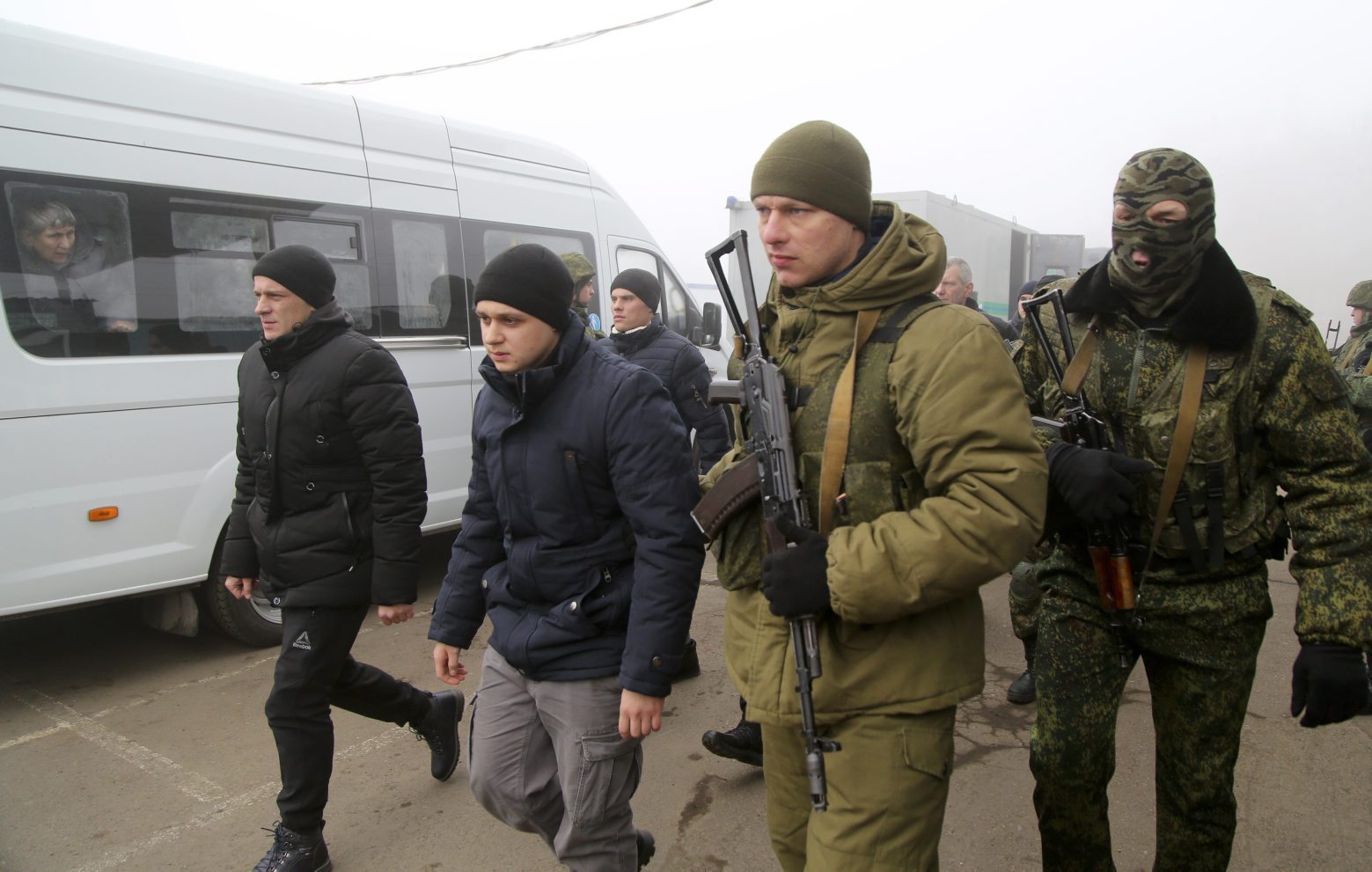 Ukrainian war prisoners escorted by armed Russia-backed separatist soldiers walk to buses to be exchanged near the checkpoint Horlivka, eastern Ukraine, Sunday, Dec. 29, 2019. Ukrainian forces and Russia-backed rebels in eastern Ukraine have begun exchanging prisoners in a move aimed at ending their five-year-long war. The move is part of an agreement brokered earlier this month at a summit of the leaders of Ukraine, Russia, Germany and France. (AP Photo/Alexei Alexandrov) Ukraine Russia Prisoners