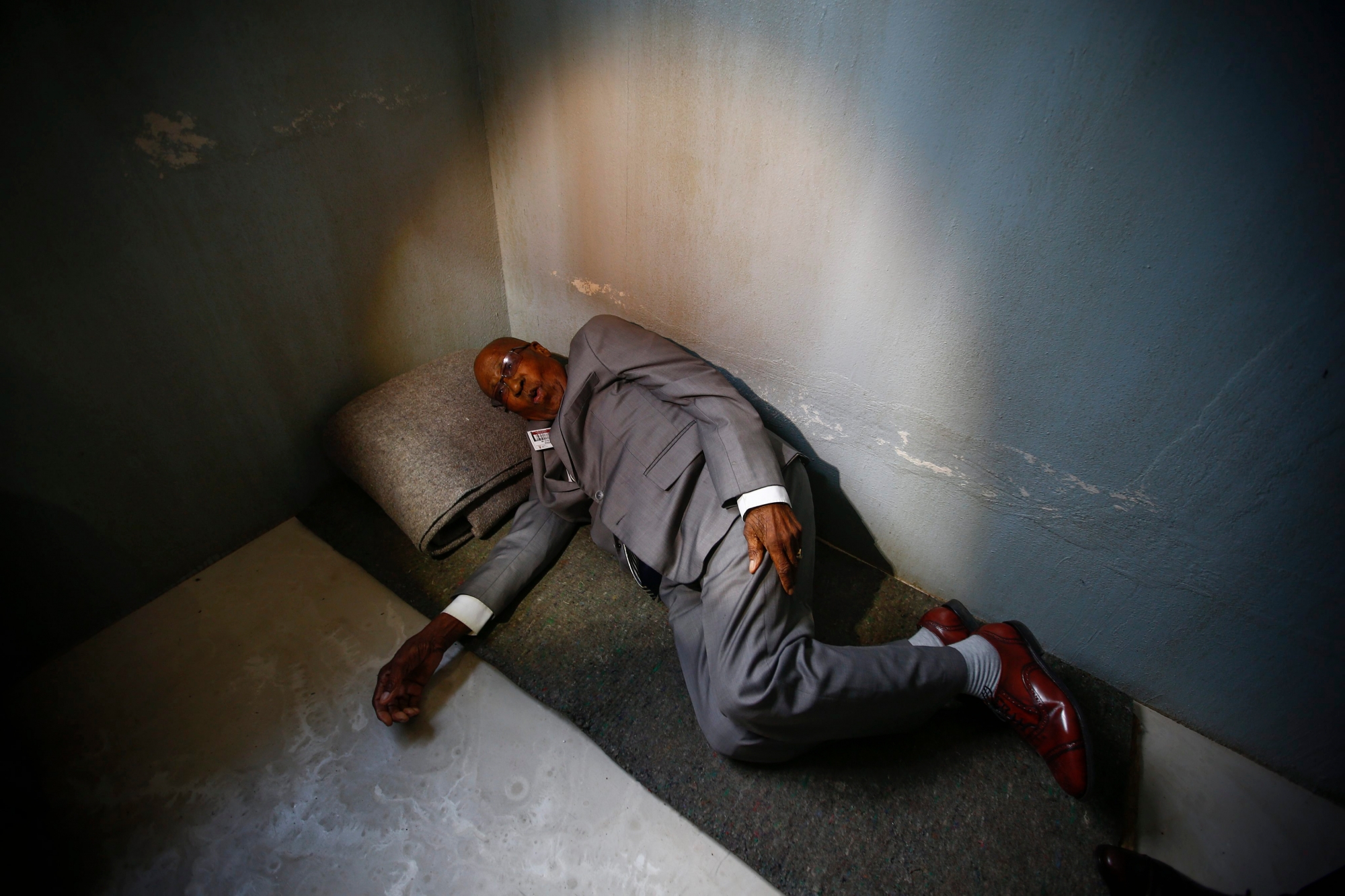 epa05556526 Andrew Mlangeni, South African political activist and former political prisoner demonstrates how he used to sleep on the floor in a prison cell during the launch of the replica of Nelson Mandela's Robben Island Prison Cell in Cape Town, South Africa, 26 September 2016. Former South African president and Nobel Peace laureate Nelson Mandela was imprisoned in a cell of these exact proportions for 27 years. This mobile replica will make its way around the country to enable young people who have never been to the Robben Island Museum to get a personal perspective of the history that unfolded on Robben Island and South Africa. EPA/NIC BOTHMA SOUTH AFRICA HISTORY MANDELA PRISON CELL REPLICA