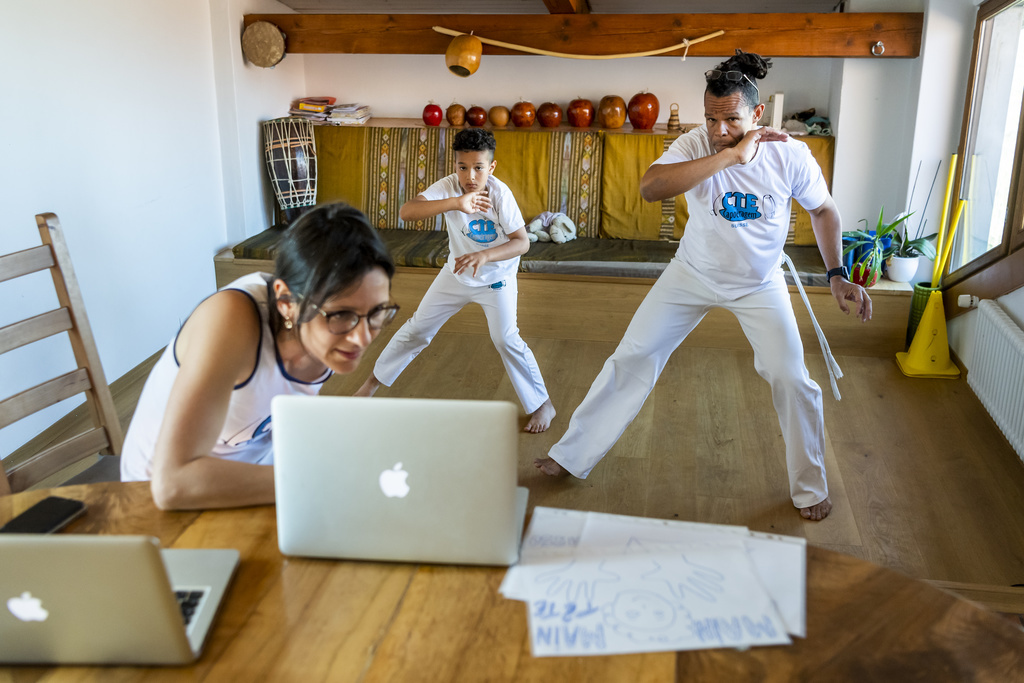 Héléna, Noah, et Mestre Papa de l'association Capoeira Neuchâtel donnent un cours de Capoeira par vidéo a des jeunes enfants depuis un appartement à Boudry pendant la crise du Coronavirus.