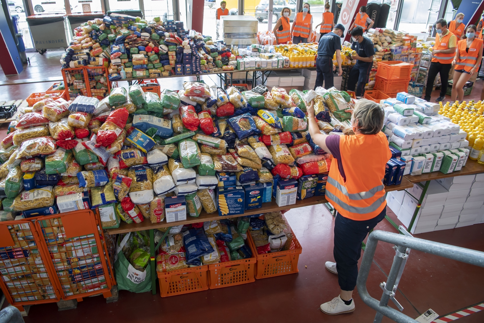 Des bénévoles s'affairent autour de la préparation de sacs alimentaires, organisée par la Caravane de la Solidarité à Genève.