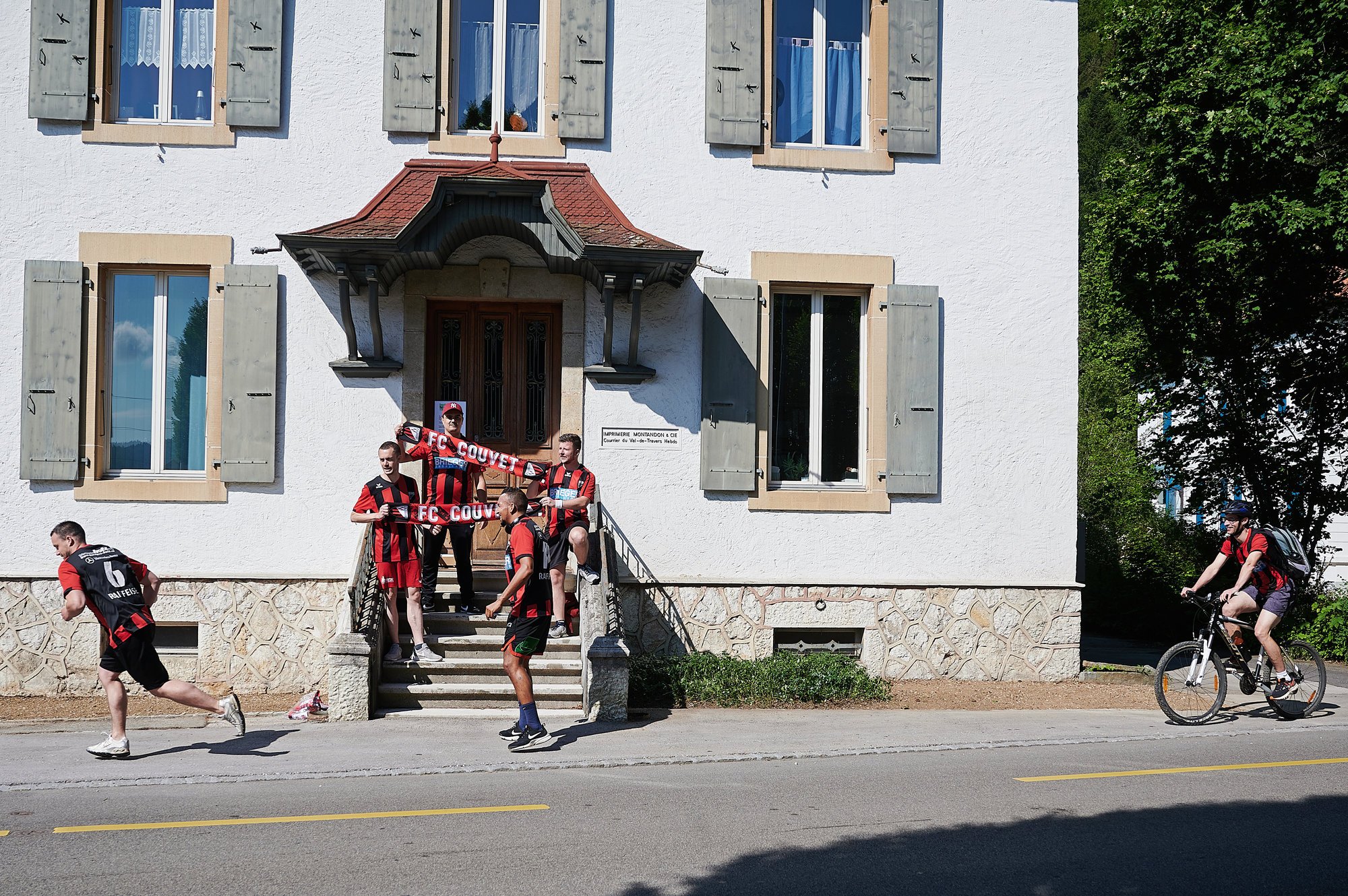 Passage de relais devant les bureaux du "Courrier du Val-de-Travers", à Fleurier, pour les joueurs du FC Couvet. A droite, le coach Raphael Claudio suit ses gars à vélo.