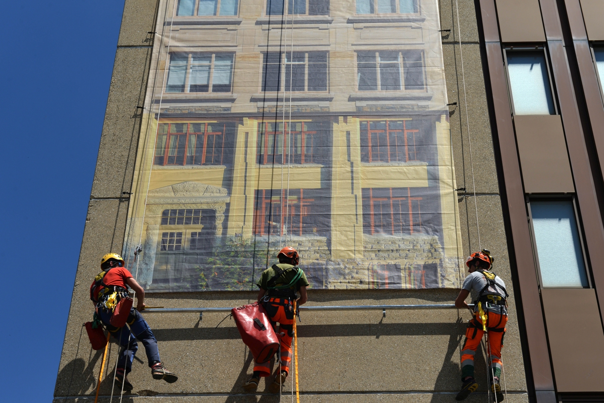 Le premier cadeau offert pour le 11e anniversaire: l'accrochage d'une bâche géante représentant des fenêtres emblématiques de La Chaux-de-Fonds sur le building de Léopold-Robert 18.