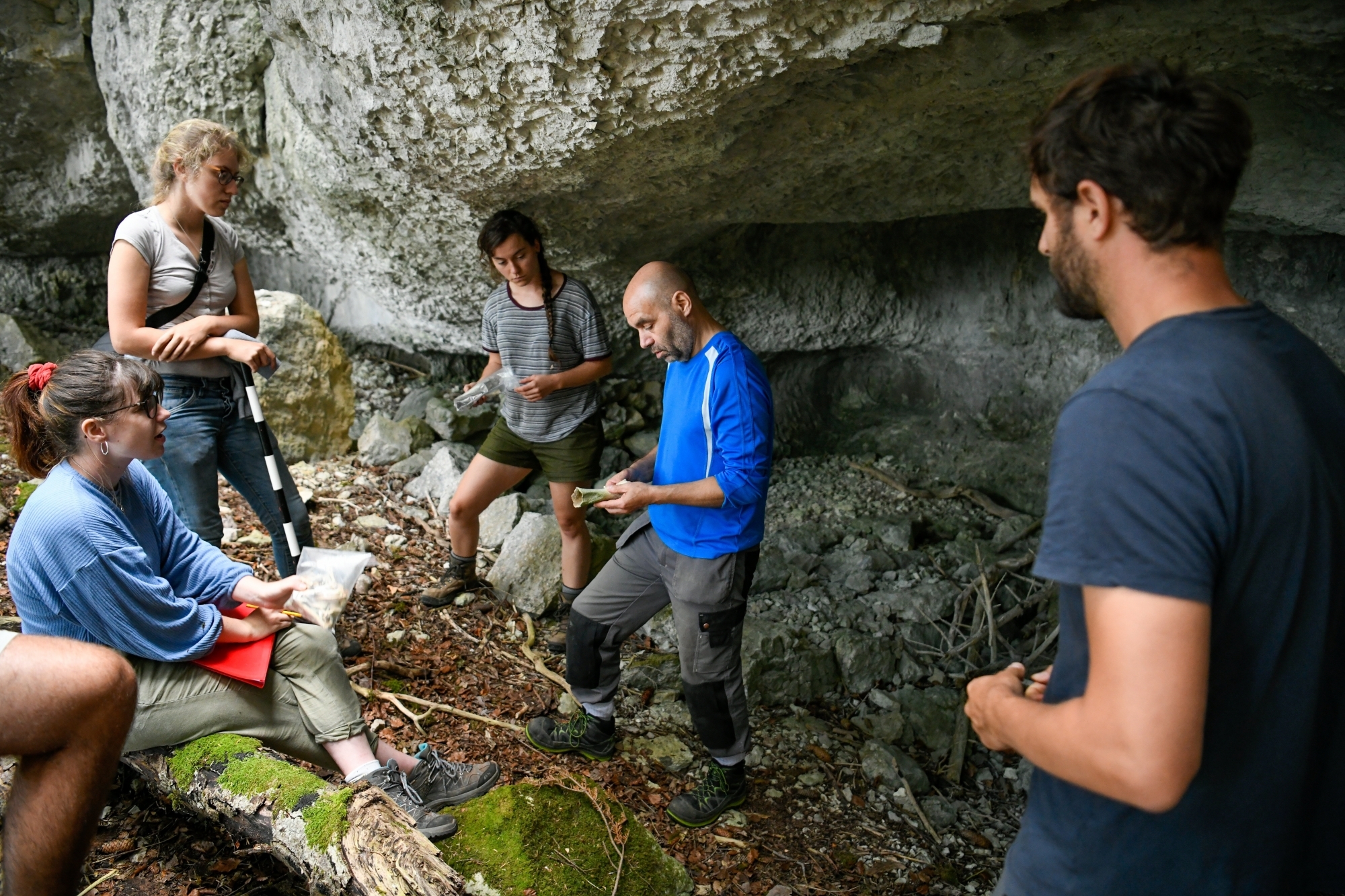 L'archéologue François-Xavier Chauvière (en centre) et l'assistant-doctorant Bastien Jakob (de dos) observent avec leurs étudiantes des os trouvés dans l'abri sous roche du Creux-du-Vent.